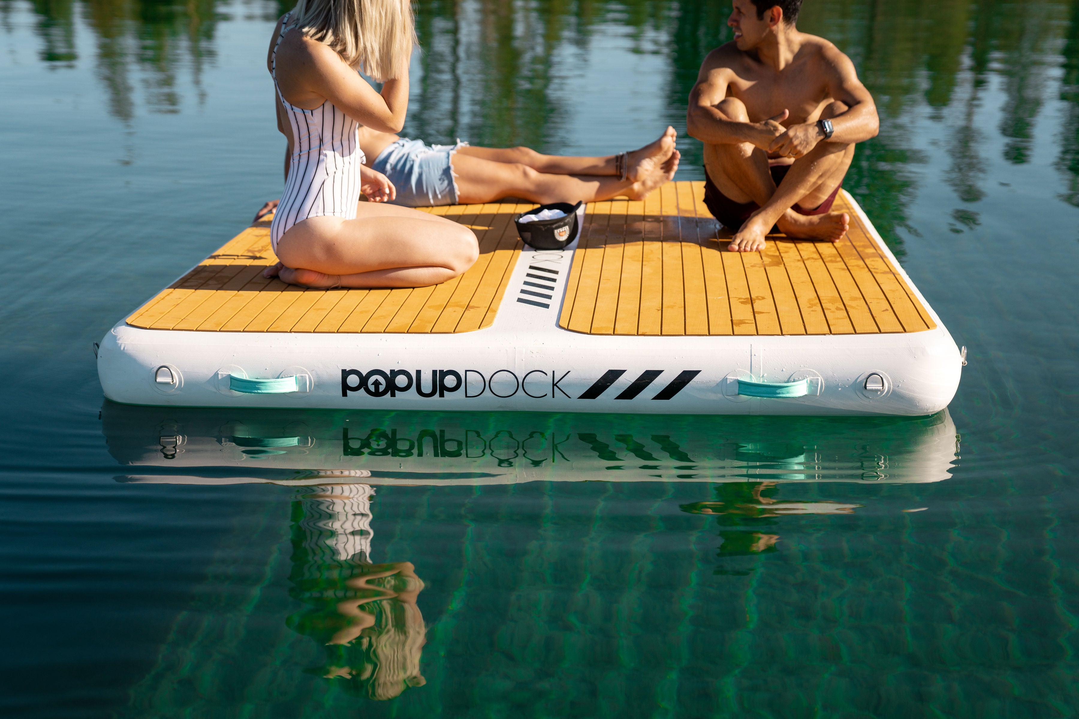 PopBoard inflatable dock floating on water with friends sitting on top. Available to buy at e-boarders.com