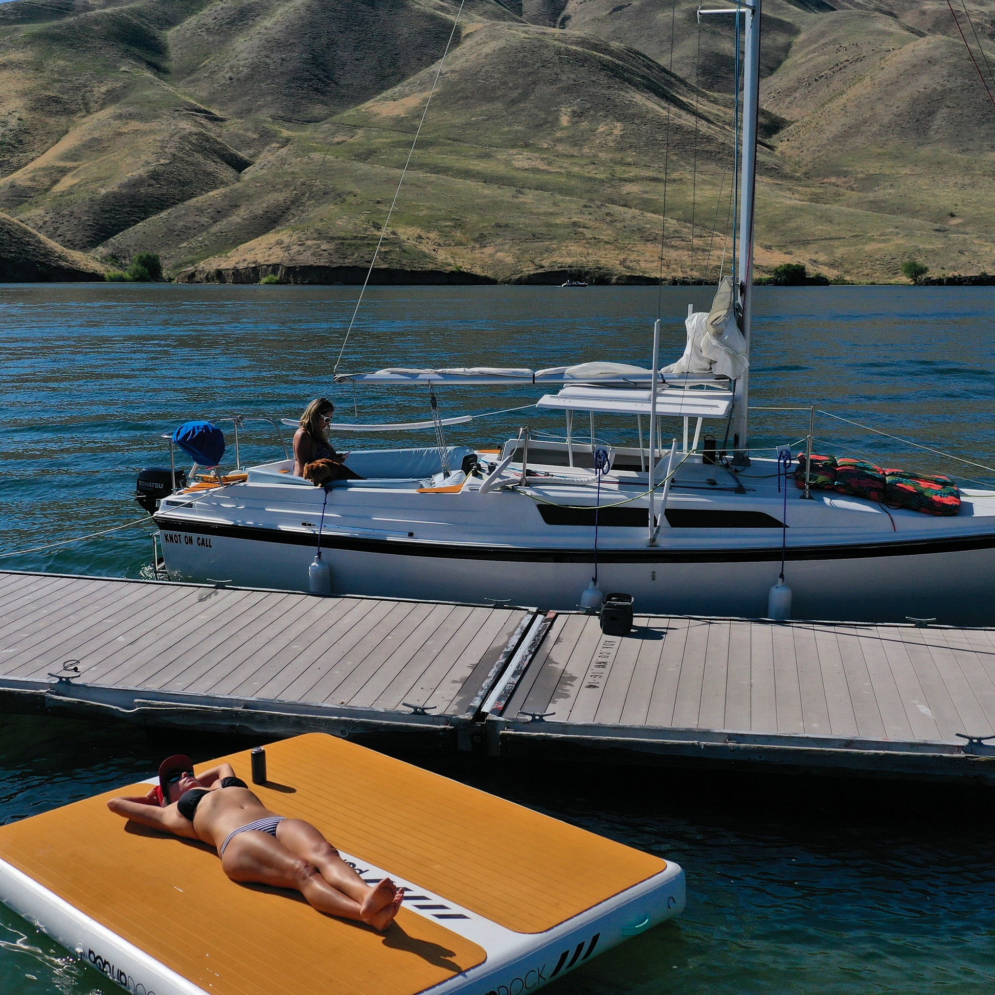 PopBoard Inflatable Dock floating on the water near a dock and a sailboat. Available at e-boarders.com