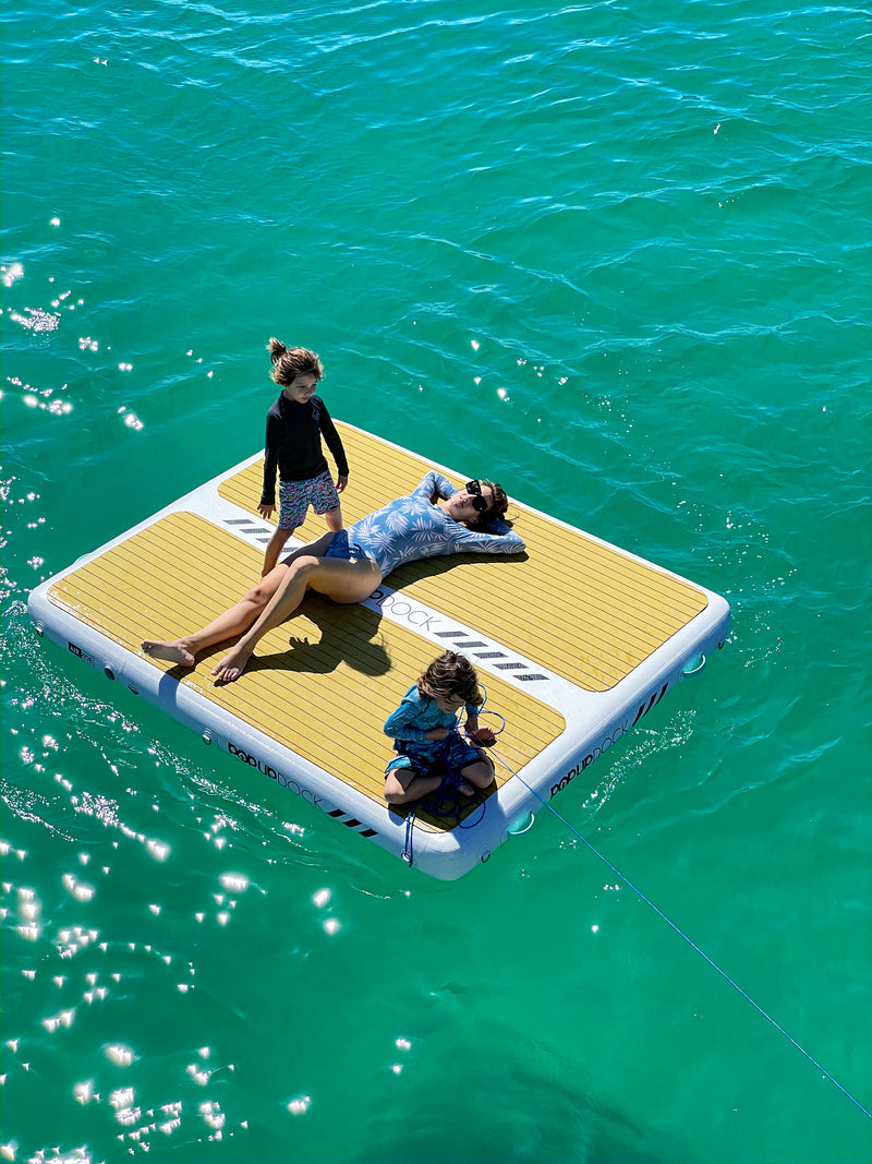 Mother and two children lounge ontop of a PopBoard PopUP Inflatable Dock Platform out in the middle of a lake.