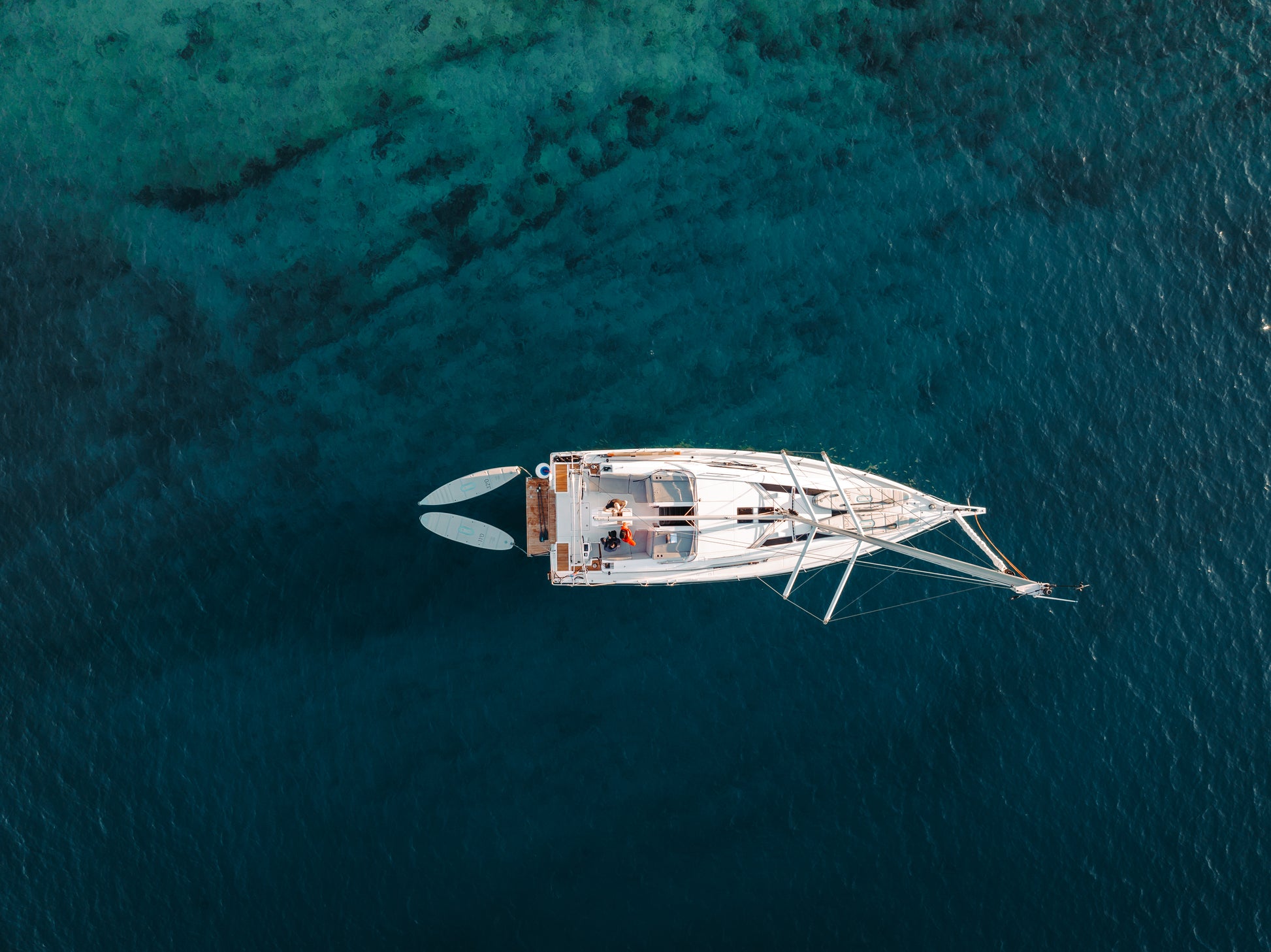 SIPA Boards Neo and Tourer Electric Paddleboard with self-inflating design and assist power unit floating on the water with sailboat. Ships free from e-boarders.com.