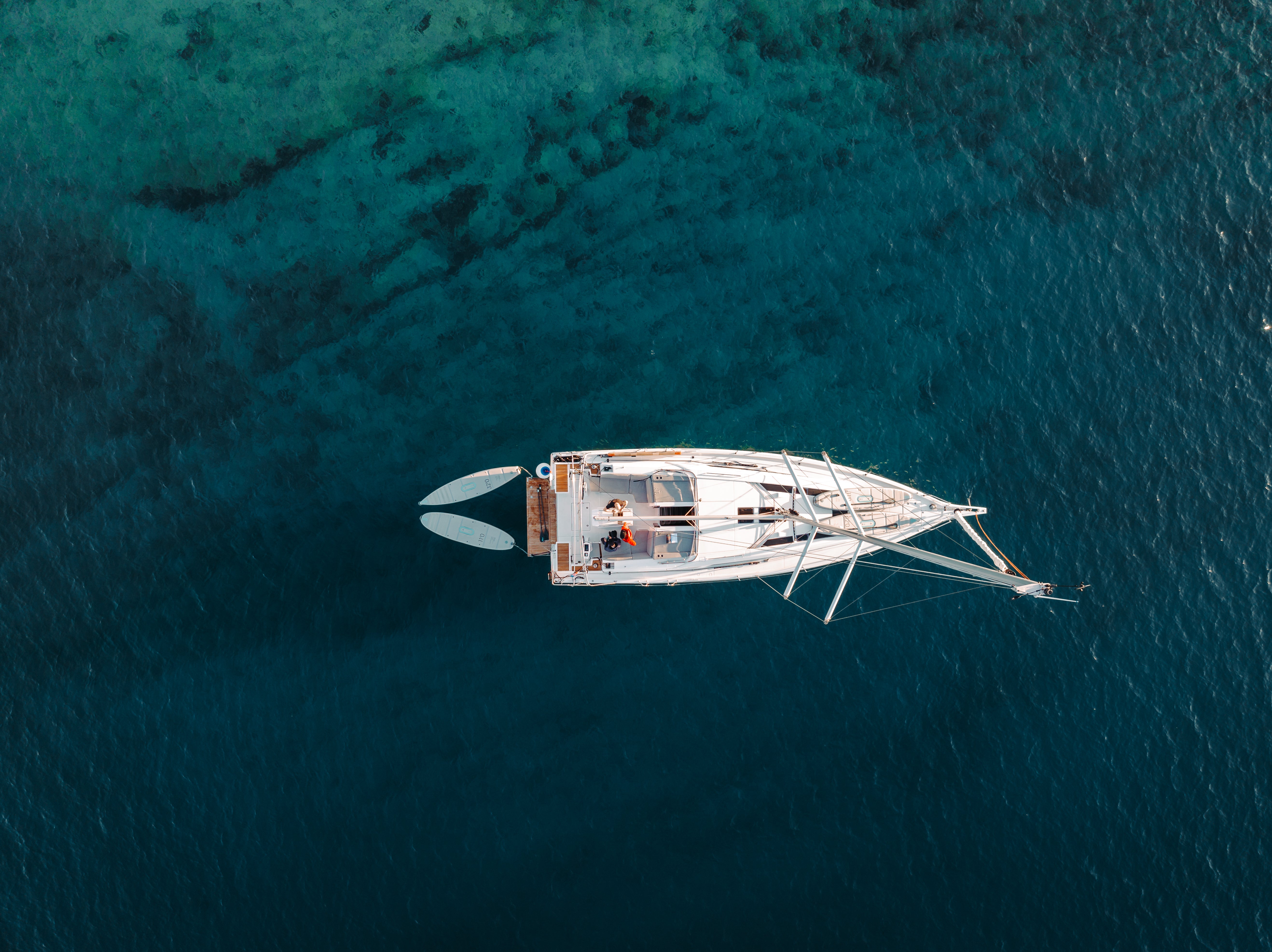 SIPA Boards Neo and Tourer Electric Paddleboard with self-inflating design and assist power unit floating on the water with sailboat. Ships free from e-boarders.com.
