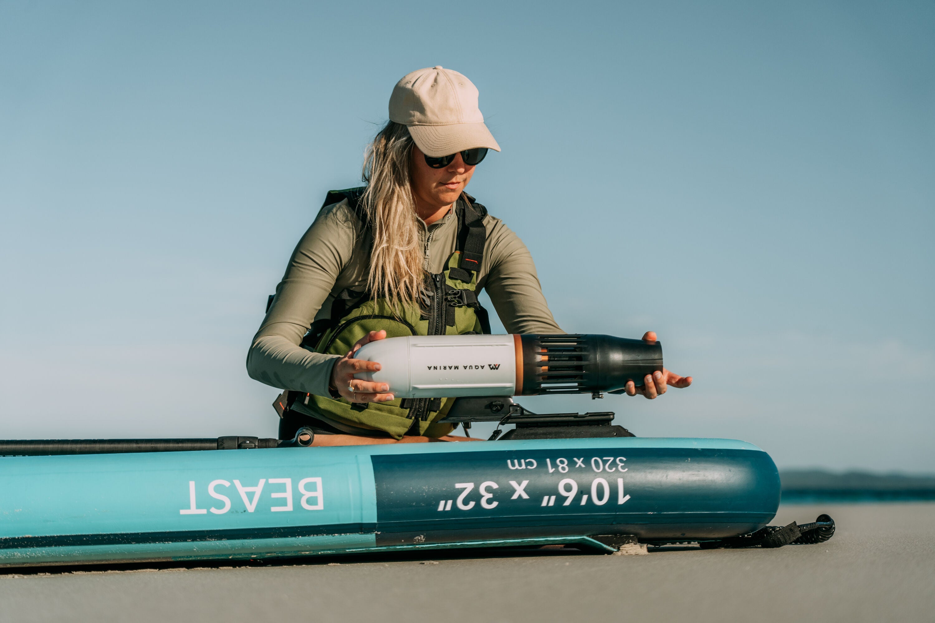 Woman mounting Aqua Marina BLUEDRIVE X Pro electric-assist fin system to a paddleboard middle fin adaptor. Free shipping at e-boarders.com