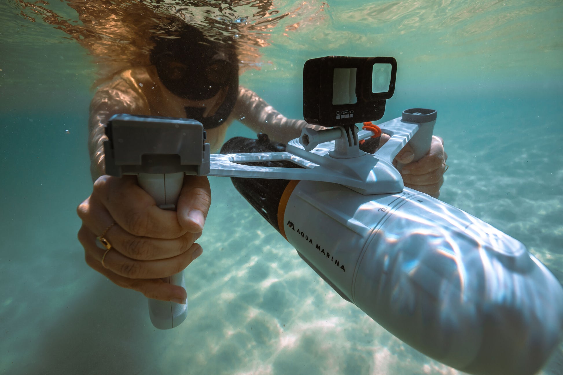 Female snorkeler underwater holding Aqua Marina Bluedrive X Pro handle bar mount with GoPro camera mount for underwater filming photography. Available with free shipping at E-Boarders.com