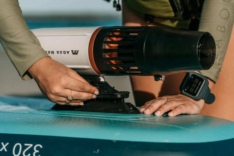 Person attaching Aqua Marina BLUEDRIVE X Pro to paddleboard middle fn adaptor. Free shipping at e-boarders.com