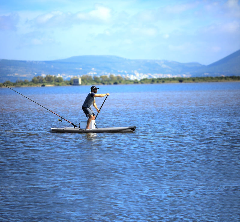 Lifestyle photo man paddling to cast a fishing rod line on Aqua Marina Drift iSUP with rod holder — ships free at e-boarders.com