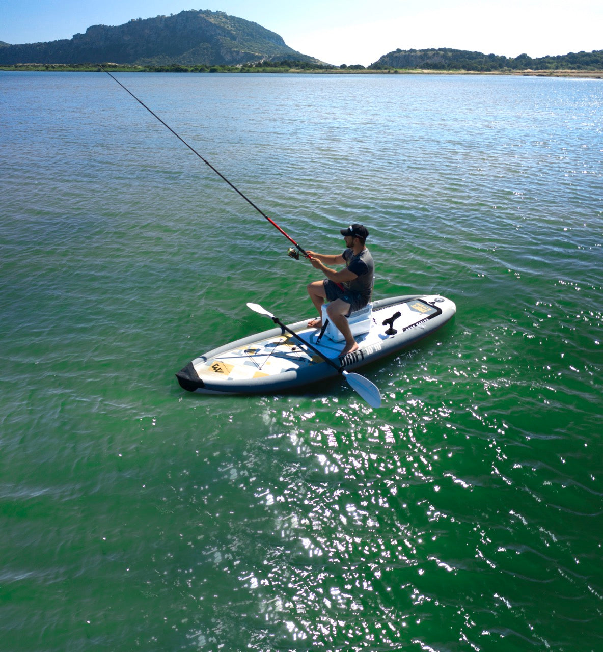 Lifestyle photo man with a fishing rod line on Aqua Marina Drift iSUP with rod holder — ships free at e-boarders.com