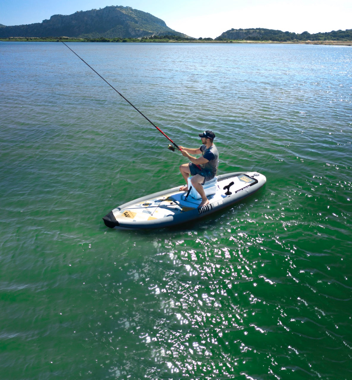 Lifestyle photo man casting a fishing rod line on Aqua Marina Drift iSUP with rod holder — ships free at e-boarders.com