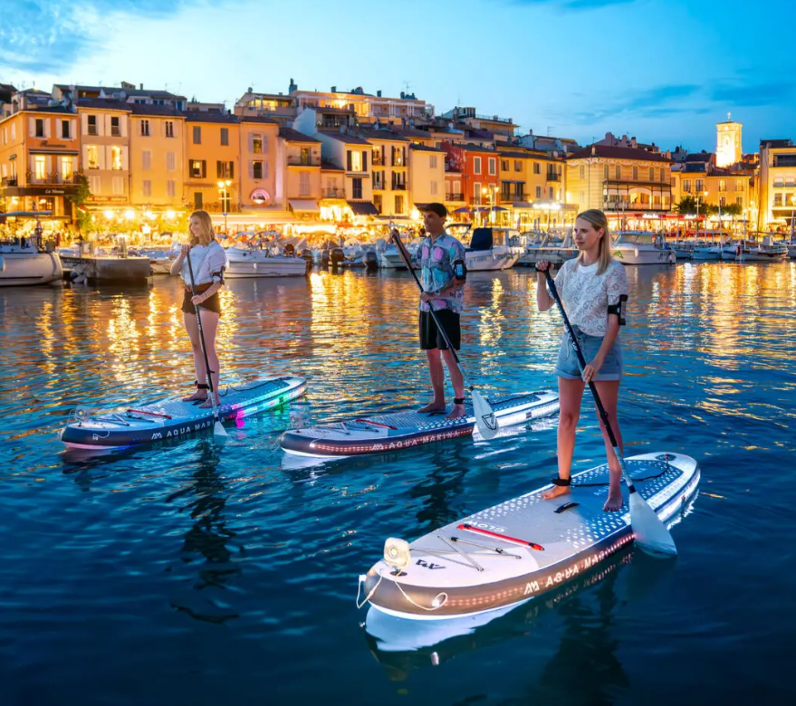 Aqua Marina Glow Paddleboards with paddlers illuminating the water around them as they paddle.