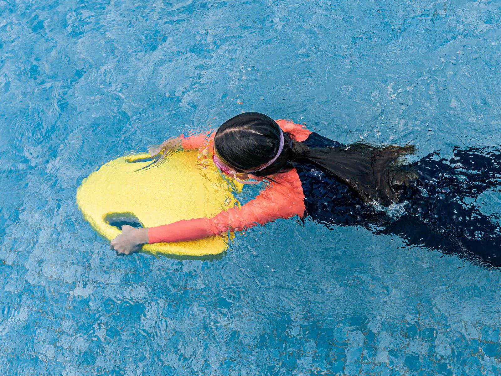 Girl swimming in pool with ASIWO MAKO electric swimming kickboard in yellow for aquatic swim assistance. Ships free at e-boarders.com