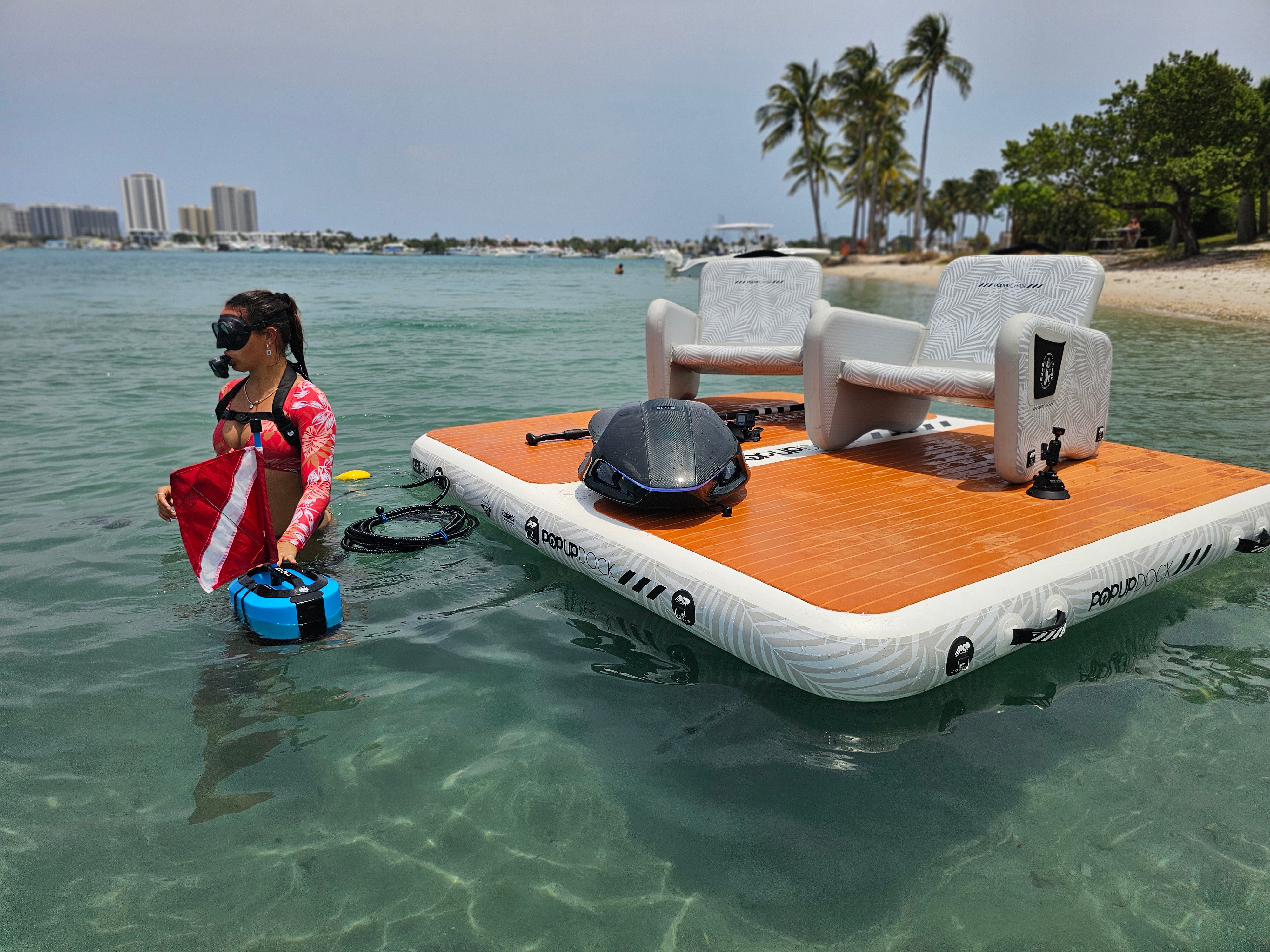 PopBoard Inflatable Dock, inflatale chair set, and inflatable Table, shown floating on the water with a scuba diver available at e-boarders.com
