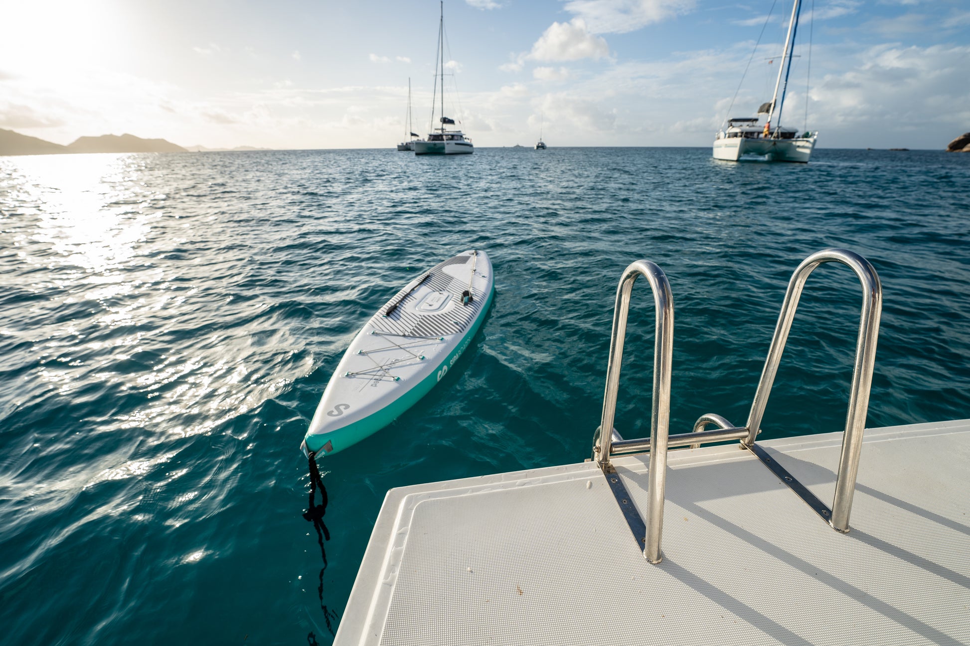 SIPA Boards Alpha One Electric Paddleboard with self-inflating design and assist power unit floating on the water with sailboats. Ships free from e-boarders.com.