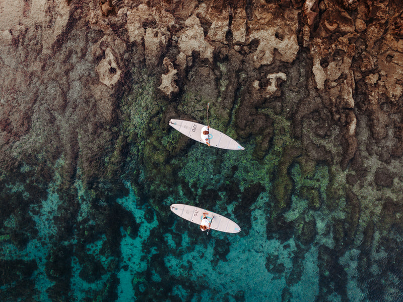 Two paddlers on SIPA Boards Alpha One Electric Paddleboard with self-inflating design and assist power unit floating on the water with sailboats. Ships free from e-boarders.com.